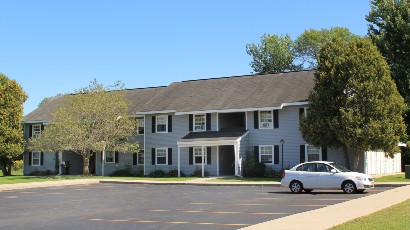 Apartments near Sackets Harbor NY thumbnail image of street view with parking lot for shipyard family apartments with playground for two plus four management